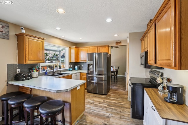 4055 NE 13th Ter, Gresham, OR 97030 - kitchen with stainless steel appliances, a sink, a peninsula, light wood-style floors, and a textured ceiling