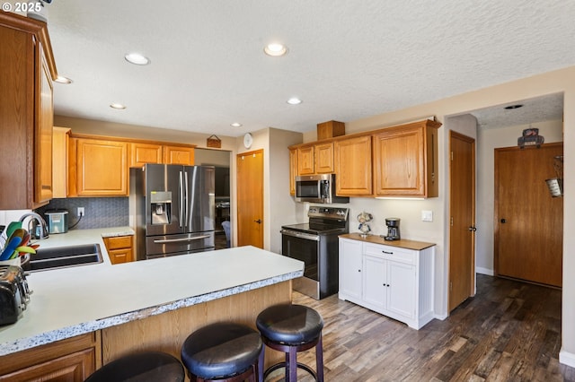 4055 NE 13th Ter, Gresham, OR 97030 - kitchen featuring stainless steel appliances, light countertops, a sink, dark wood-style flooring, and a peninsula