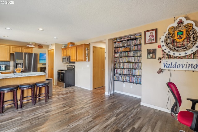 4055 NE 13th Ter, Gresham, OR 97030 - kitchen with appliances with stainless steel finishes, a textured ceiling, dark wood finished floors, a kitchen bar, and light countertops