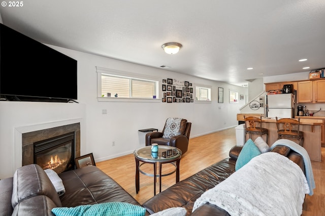 12631 SE Division St, Portland, OR 97236 - living room featuring visible vents, baseboards, recessed lighting, light wood-style flooring, and a glass covered fireplace