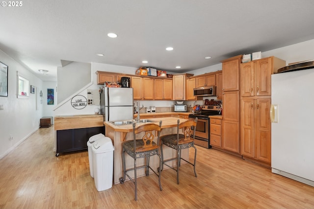 12631 SE Division St, Portland, OR 97236 - kitchen featuring a sink, light wood-type flooring, an island with sink, and stainless steel appliances