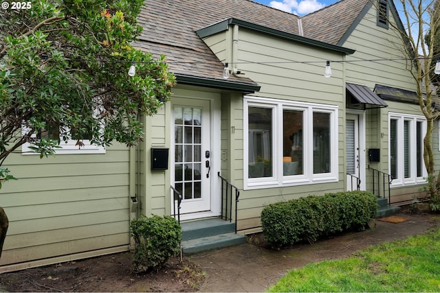 entrance to property featuring a shingled roof