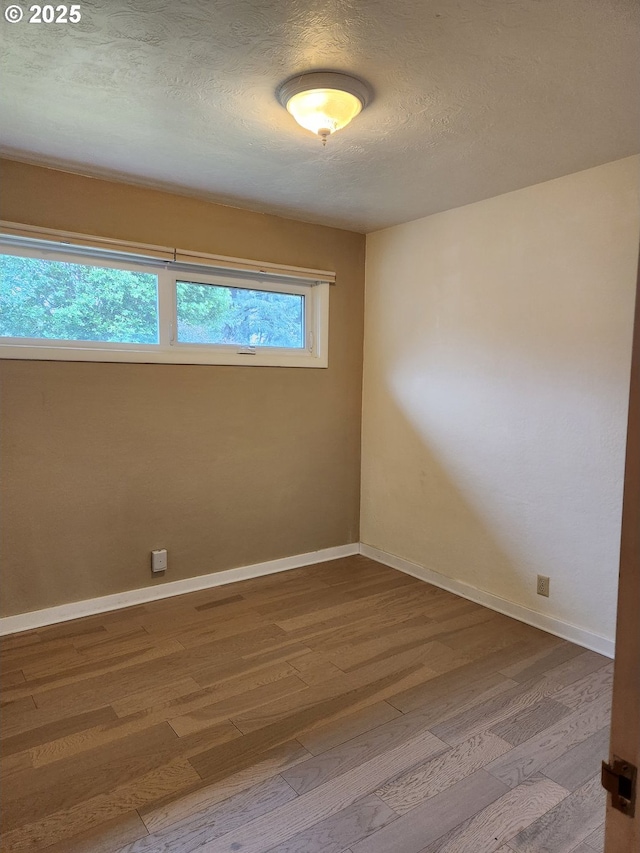 spare room featuring hardwood / wood-style floors and a textured ceiling