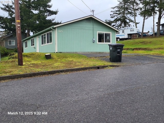 view of side of property with driveway and a yard