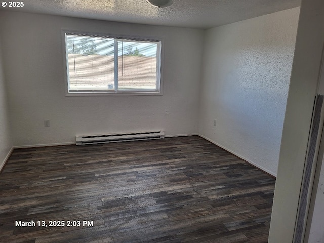spare room featuring dark wood-style floors, baseboard heating, and a textured ceiling