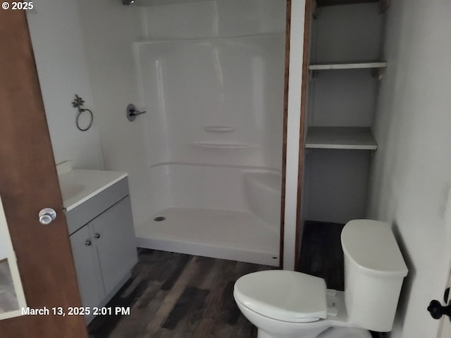 full bathroom featuring vanity, toilet, wood finished floors, and a stall shower