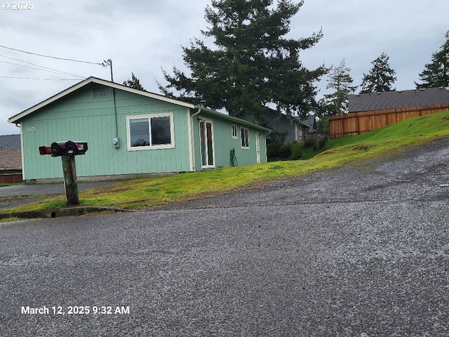 view of side of home featuring fence and a lawn