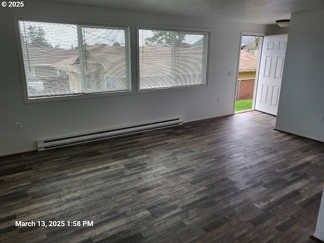 unfurnished room featuring dark wood finished floors, baseboard heating, and a textured ceiling