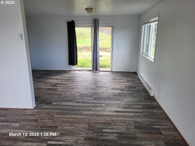 unfurnished room featuring a baseboard heating unit, a textured wall, plenty of natural light, a textured ceiling, and dark wood-style flooring