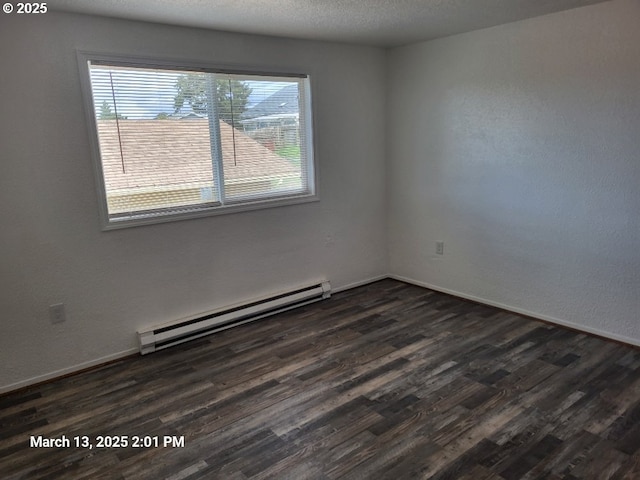 spare room featuring baseboards, dark wood-type flooring, baseboard heating, and a textured ceiling