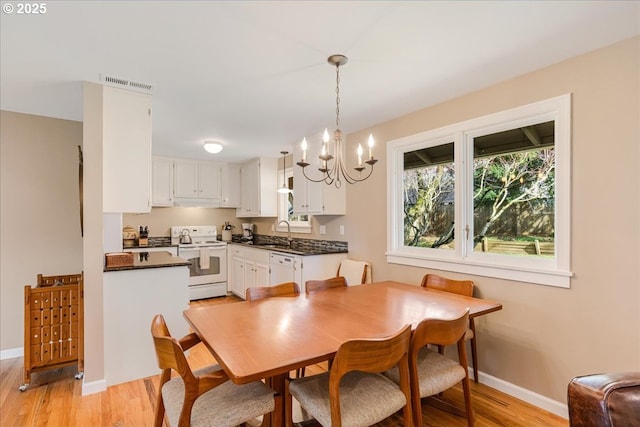 dining room with light wood finished floors, visible vents, a notable chandelier, and baseboards