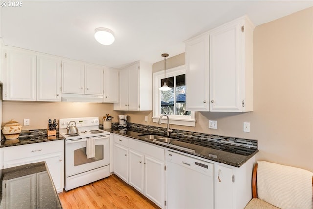 kitchen with white appliances, white cabinets, dark stone countertops, and a sink