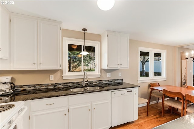 kitchen with dark stone counters, light wood-style floors, white cabinets, white appliances, and a sink