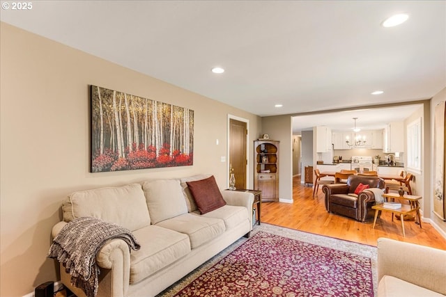 living area with recessed lighting, a chandelier, baseboards, and light wood-style flooring