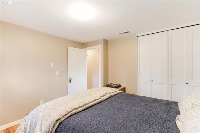 bedroom featuring a closet, visible vents, light wood-type flooring, and baseboards