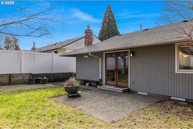 back of property featuring a patio, french doors, roof with shingles, and fence