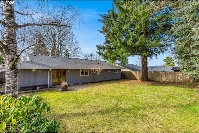 rear view of house with a yard and fence