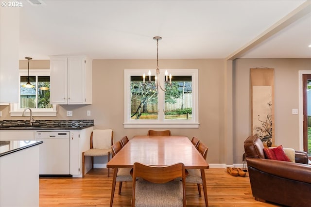 dining area with a notable chandelier, light wood-type flooring, and baseboards