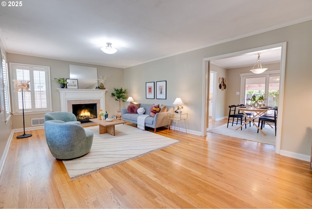 7067 N Dwight Ave, Portland, OR 97203 - living room with a lit fireplace, light wood-type flooring, and ornamental molding
