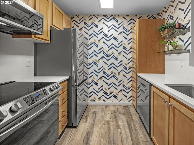 kitchen with stainless steel appliances, exhaust hood, and light hardwood / wood-style floors