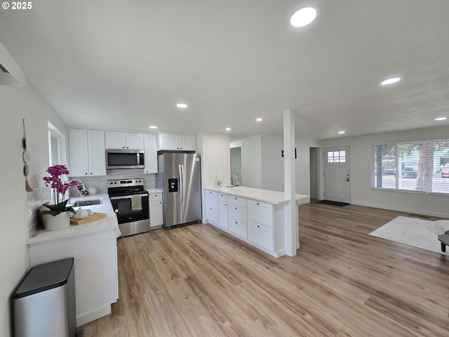 550 NE 20th Dr, Gresham, OR 97030 - kitchen featuring stainless steel appliances, a peninsula, light countertops, recessed lighting, and light wood-style floors