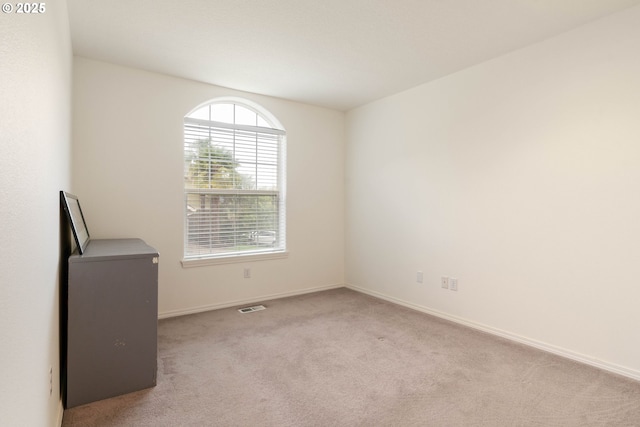 carpeted spare room with visible vents and baseboards