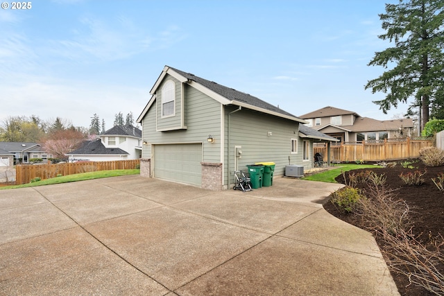 view of side of home featuring central air condition unit, fence, a garage, and driveway