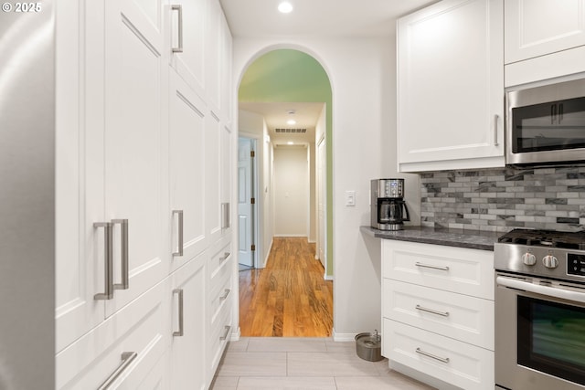 kitchen with dark stone countertops, visible vents, appliances with stainless steel finishes, white cabinetry, and backsplash