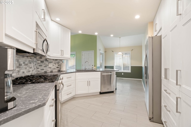 kitchen with appliances with stainless steel finishes, white cabinetry, a peninsula, and a sink