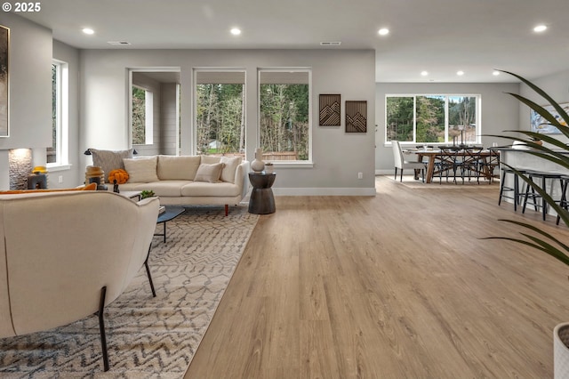 living area with recessed lighting, baseboards, visible vents, and wood finished floors