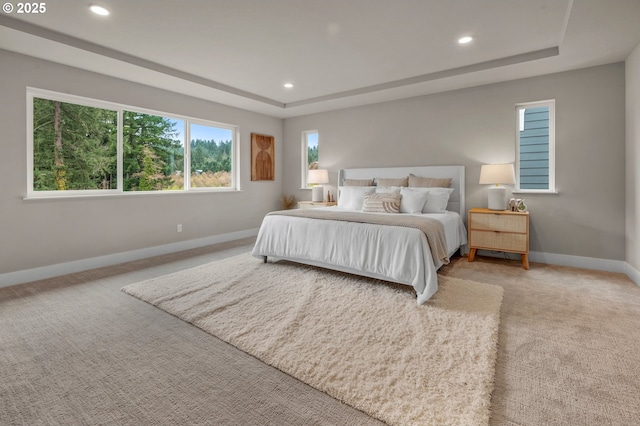 bedroom with a raised ceiling, baseboards, recessed lighting, and light colored carpet