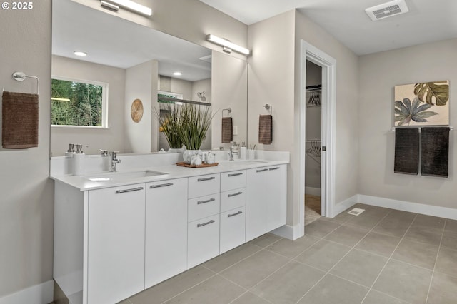 bathroom featuring a sink, a walk in closet, double vanity, and visible vents