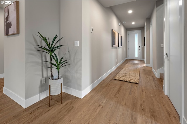 hall featuring baseboards, recessed lighting, and wood finished floors