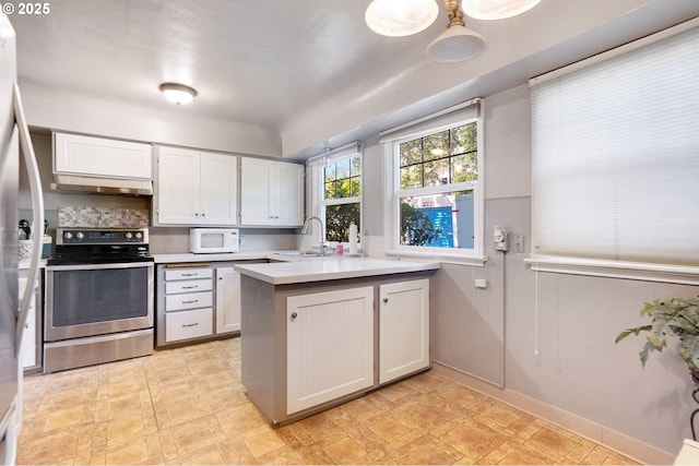 3374 Pioneer Dr, Salem, OR 97302 - kitchen with appliances with stainless steel finishes, a peninsula, light countertops, under cabinet range hood, and light flooring