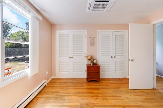 3374 Pioneer Dr, Salem, OR 97302 - bedroom featuring a baseboard heating unit, two closets, and light wood finished floors