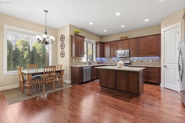 27387 SW Copper Creek Loop, Wilsonville, OR 97070 - kitchen with stainless steel appliances, dark wood finished floors, a chandelier, tasteful backsplash, and a center island