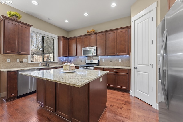 27387 SW Copper Creek Loop, Wilsonville, OR 97070 - kitchen with appliances with stainless steel finishes, dark wood-style flooring, a kitchen island, recessed lighting, and backsplash