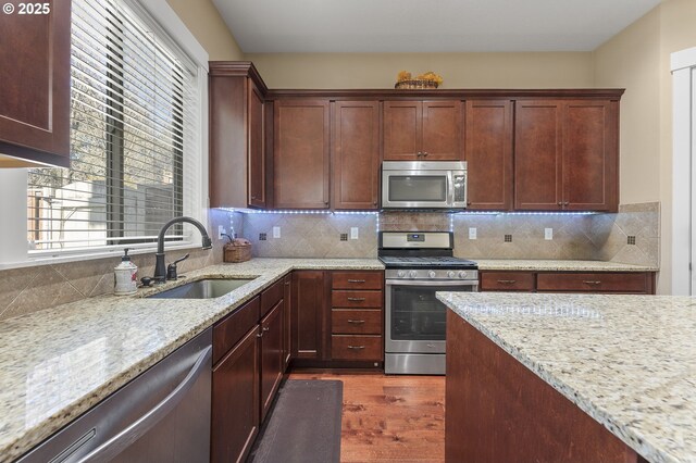 27387 SW Copper Creek Loop, Wilsonville, OR 97070 - kitchen featuring appliances with stainless steel finishes, wood finished floors, light stone counters, and backsplash