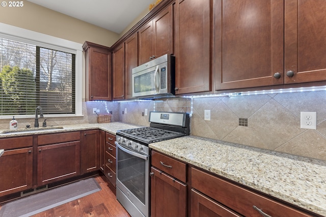 27387 SW Copper Creek Loop, Wilsonville, OR 97070 - kitchen featuring stainless steel appliances, dark wood finished floors, decorative backsplash, and light stone counters