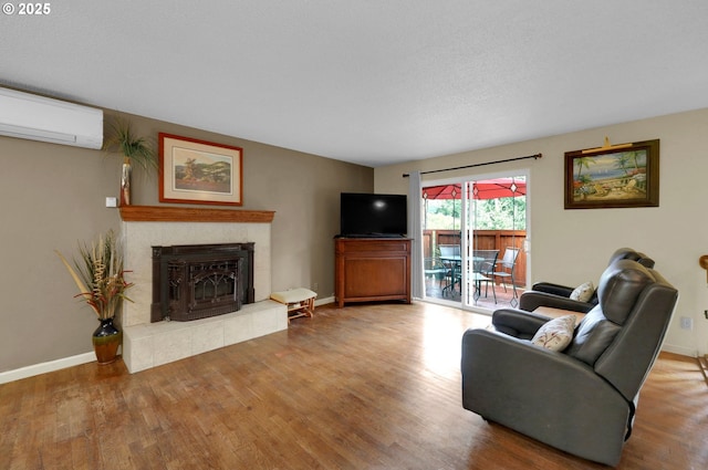 4574 Manzanita St, Eugene, OR 97405 - living room with a wall mounted air conditioner, wood finished floors, a tiled fireplace, and baseboards