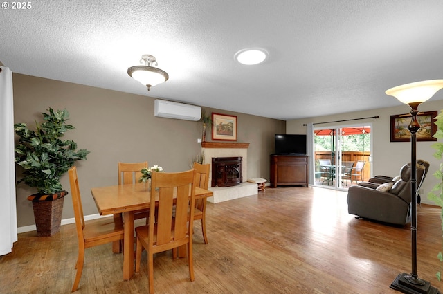 4574 Manzanita St, Eugene, OR 97405 - dining space with a wall mounted air conditioner, light wood finished floors, a fireplace with raised hearth, and a textured ceiling