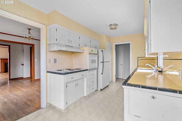 4715 N Willamette Blvd, Portland, OR 97203 - kitchen with white appliances, under cabinet range hood, wallpapered walls, tile countertops, and a chandelier