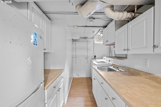 4715 N Willamette Blvd, Portland, OR 97203 - kitchen with freestanding refrigerator, white cabinets, light wood-style flooring, light countertops, and washer / dryer