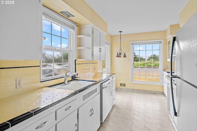 4715 N Willamette Blvd, Portland, OR 97203 - kitchen with freestanding refrigerator, dishwasher, tile countertops, open shelves, and white cabinets