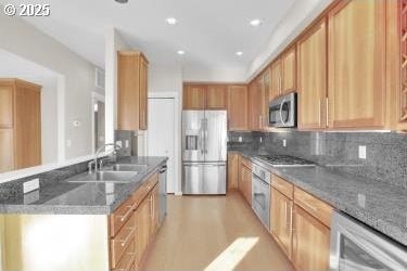 kitchen featuring sink, dark stone counters, appliances with stainless steel finishes, and tasteful backsplash