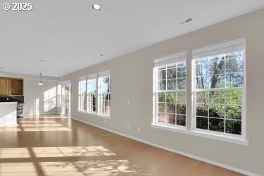 unfurnished living room featuring a wealth of natural light and wood-type flooring