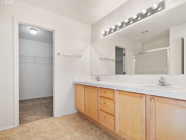 full bath with visible vents, a sink, a shower stall, and double vanity