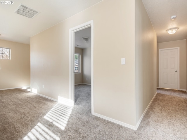 corridor featuring baseboards, visible vents, and carpet flooring