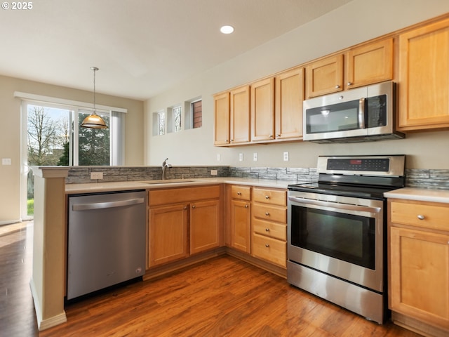 kitchen with dark wood finished floors, light brown cabinetry, appliances with stainless steel finishes, a sink, and a peninsula