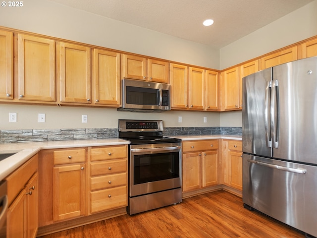 kitchen featuring light countertops, appliances with stainless steel finishes, wood finished floors, and recessed lighting